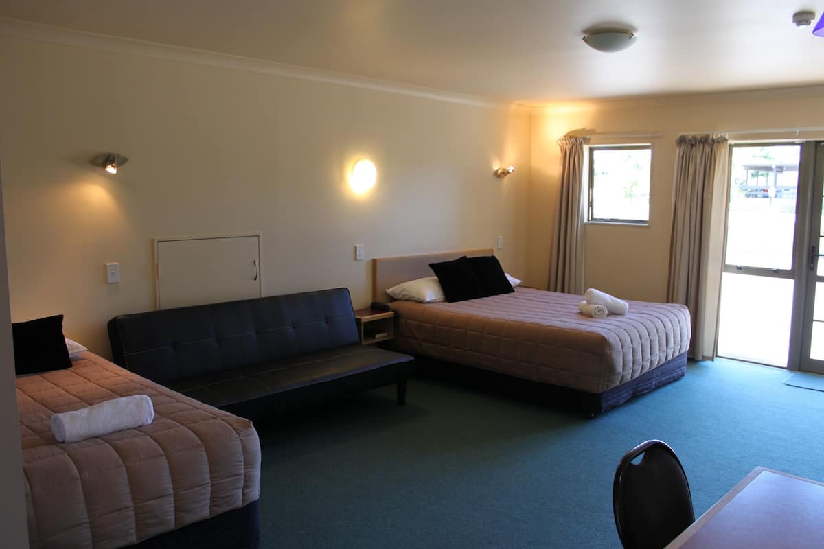 A hotel room with two beds, a sofa, a desk, and a chair.