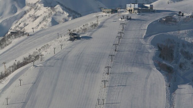 A snow-covered mountain with a ski lift and buildings at the base. - Hakuba Mominoki Hotel (Hakuba)