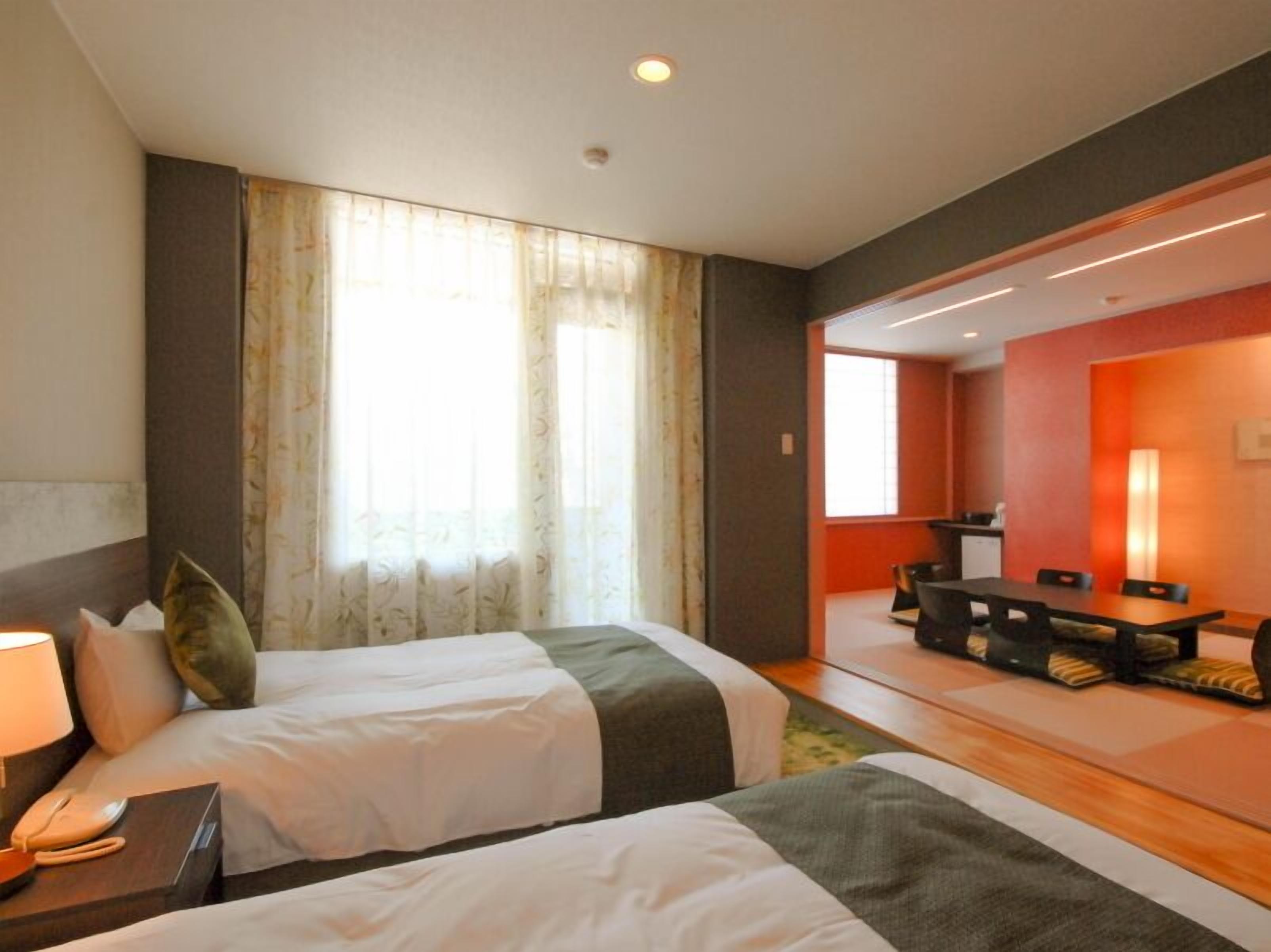 Een hotelkamer met twee bedden, een bureau en een eethoek.