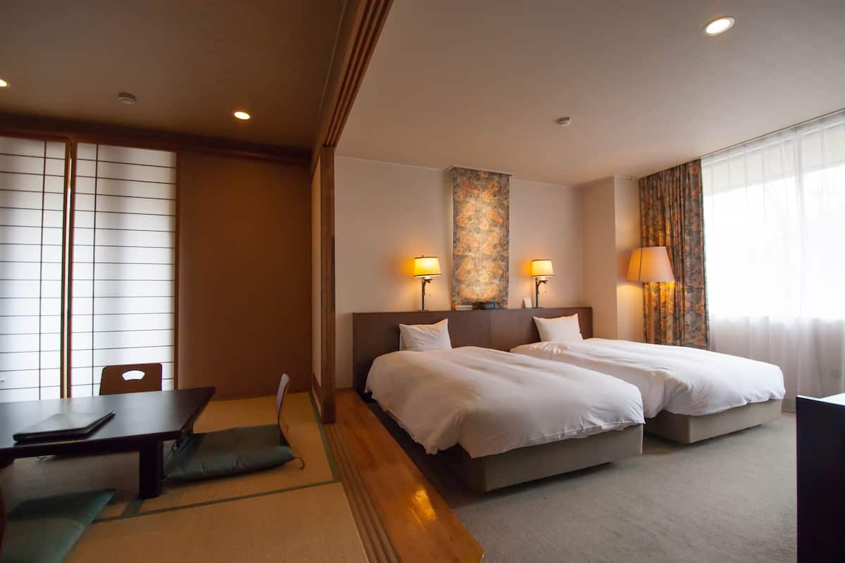 A hotel room with two beds, a desk, and a chair.