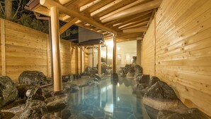A traditional wooden bathhouse with a clear stone pool surrounded by rocks. - Hakuba Mominoki Hotel (Hakuba)