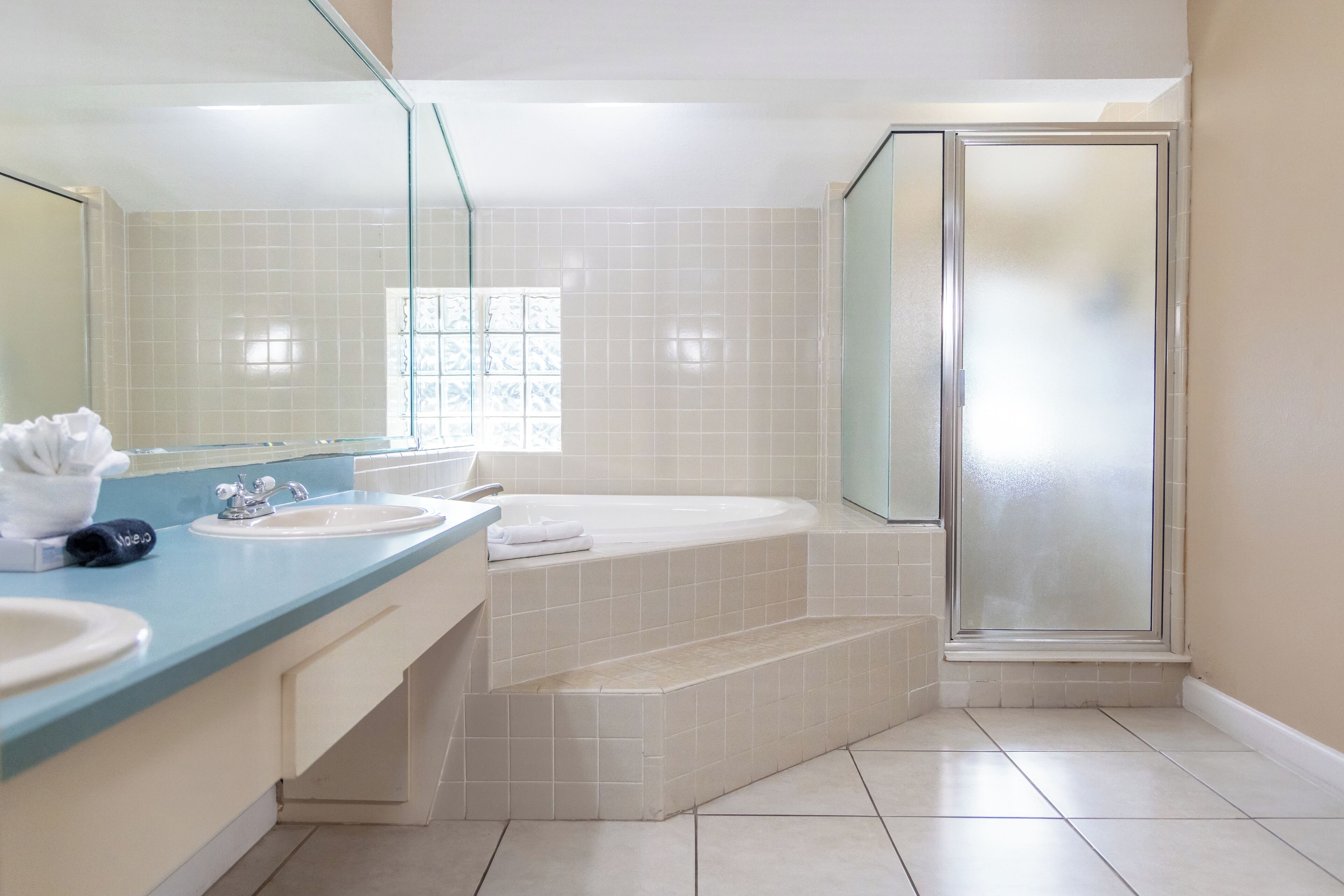 Ein Badezimmer mit einem großen Spiegel, zwei Waschbecken, einer Badewanne und einer Duschkabine aus Glas.