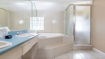 A bathroom with a large mirror, two sinks, a bathtub, and a glass shower enclosure.