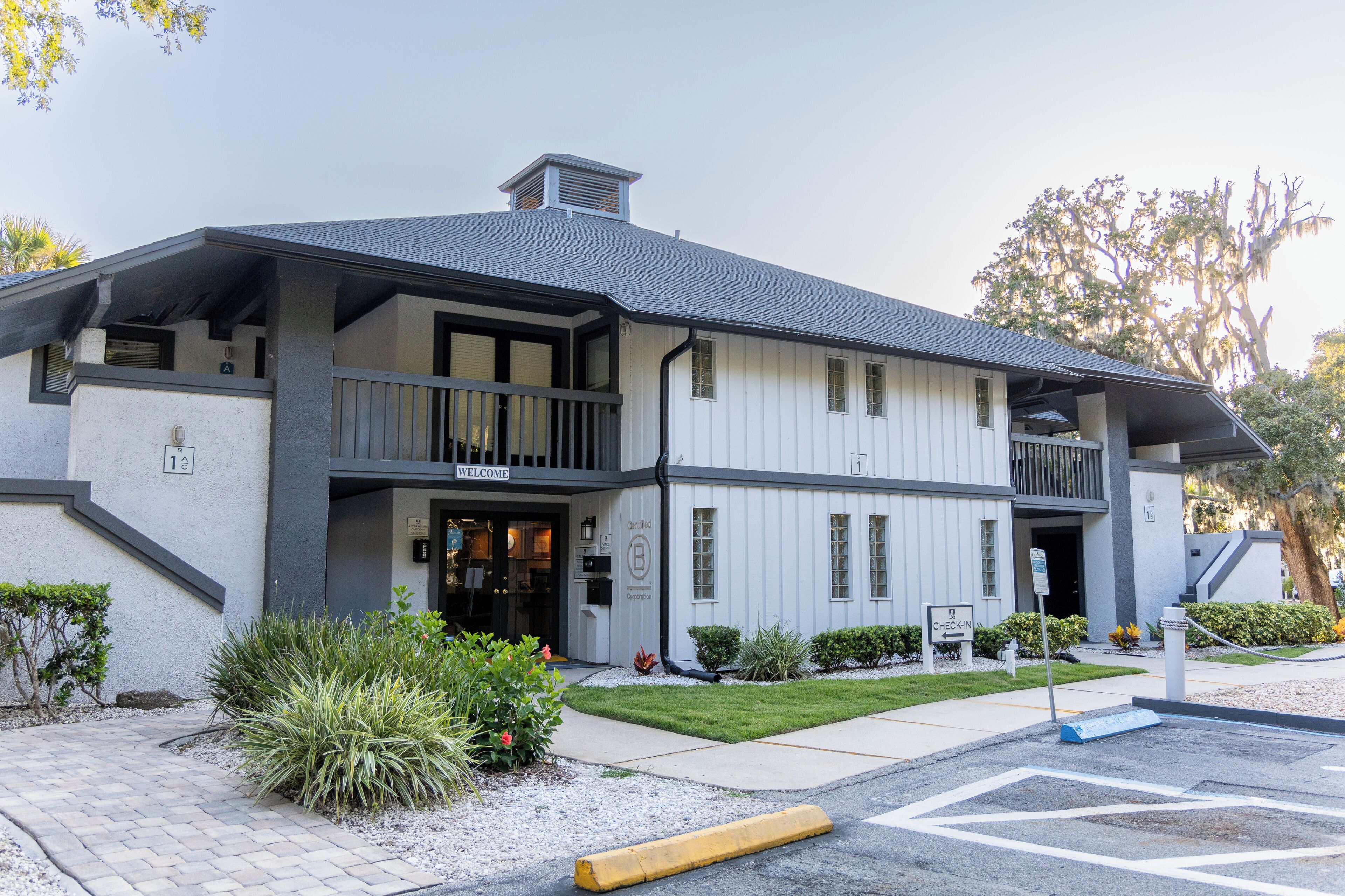 A two-story building with a balcony, a sign reading "Welcome," and a "Check-in" sign outside.