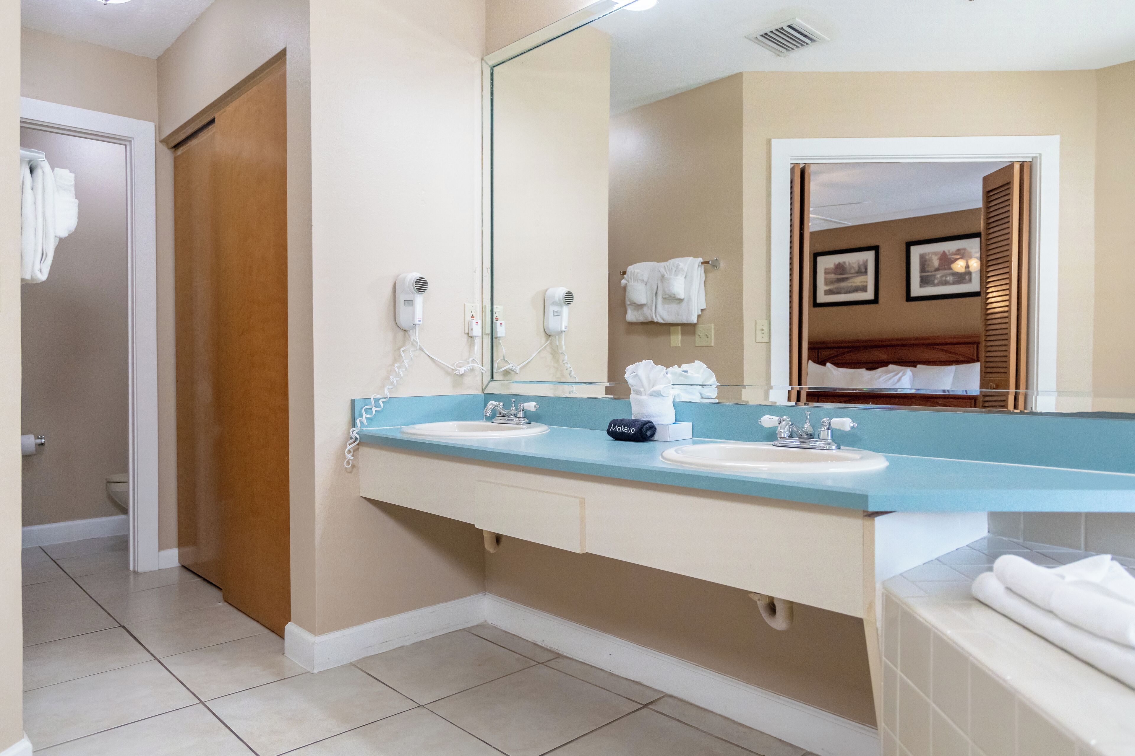 A bathroom with two sinks, a large mirror, and a towel rack.