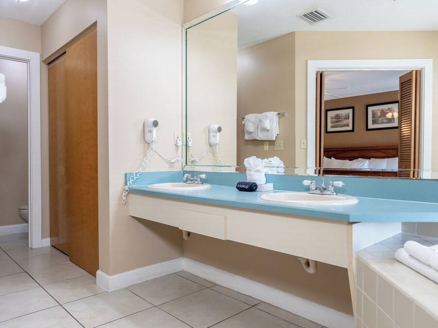 A bathroom with two sinks, a large mirror, and a towel rack.