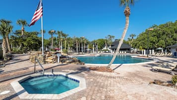 Zona de piscina con dos piscinas, palmeras y una bandera.