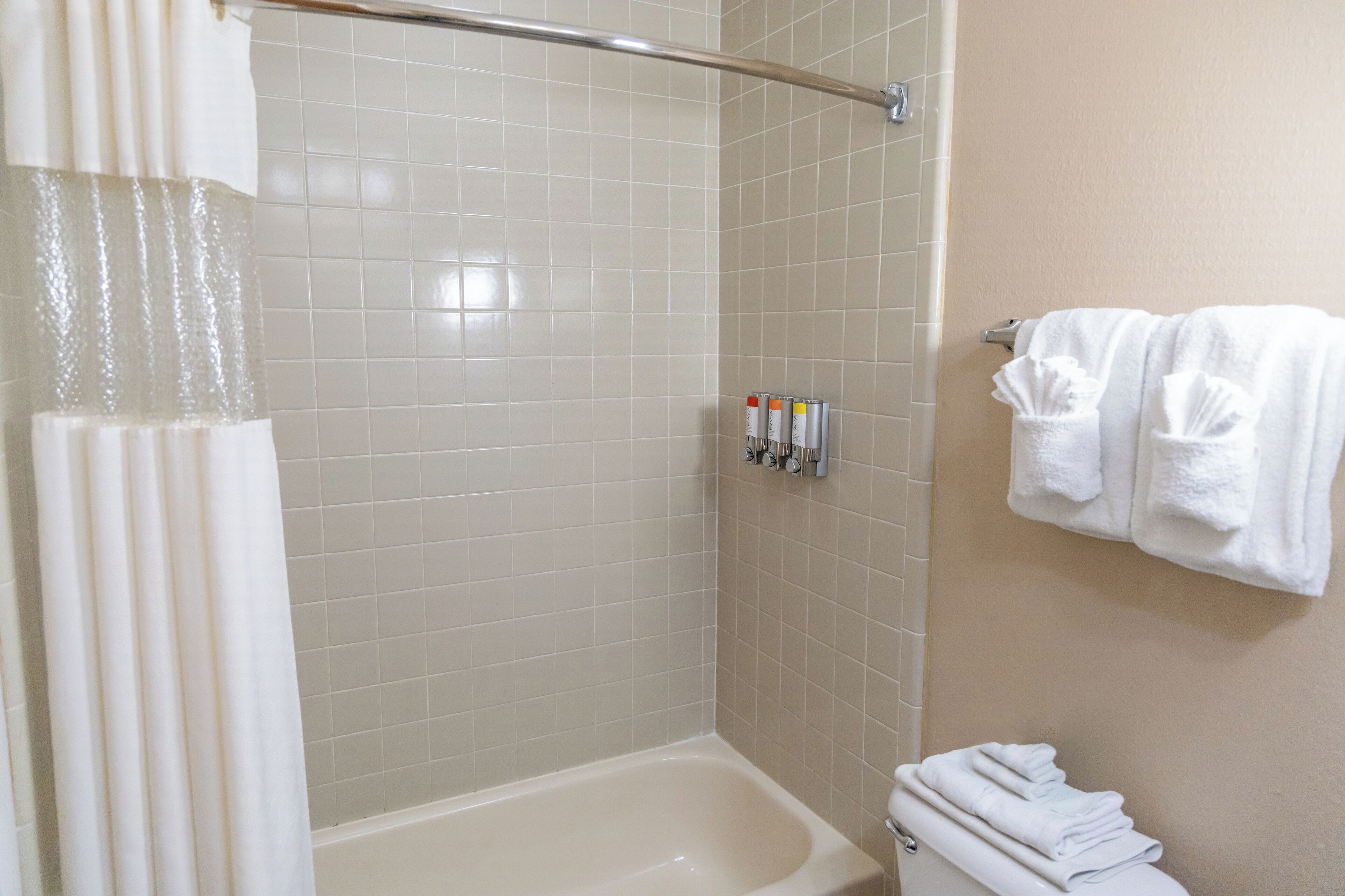 A bathroom with a bathtub, a shower curtain, and a towel rack with towels.