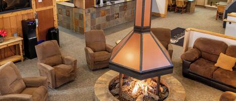 Un área de recepción con chimenea de piedra, varios sofás y un mostrador de atención al cliente.
