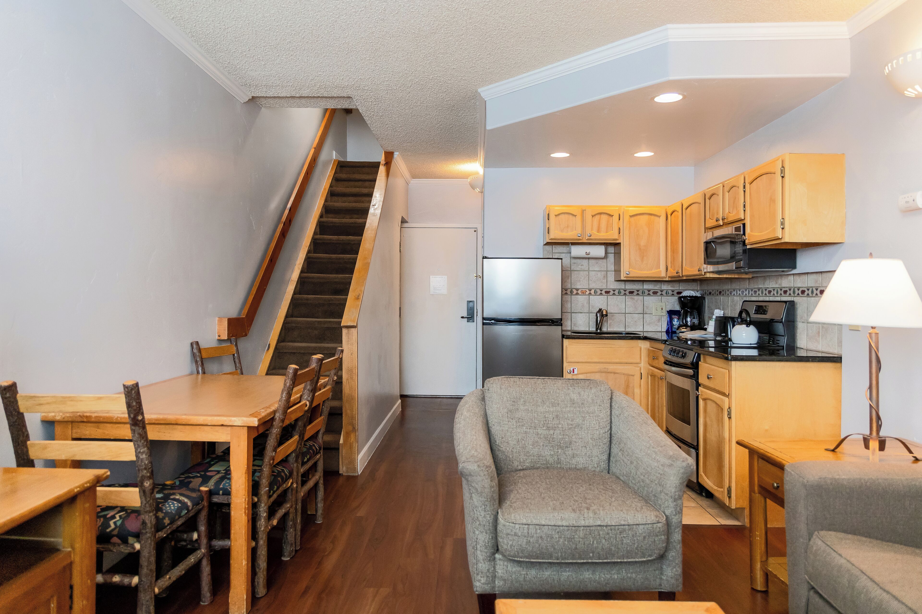 A compact kitchen with wooden cabinets, a built-in microwave, and a refrigerator.