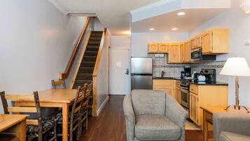 A compact kitchen with wooden cabinets, a built-in microwave, and a refrigerator.