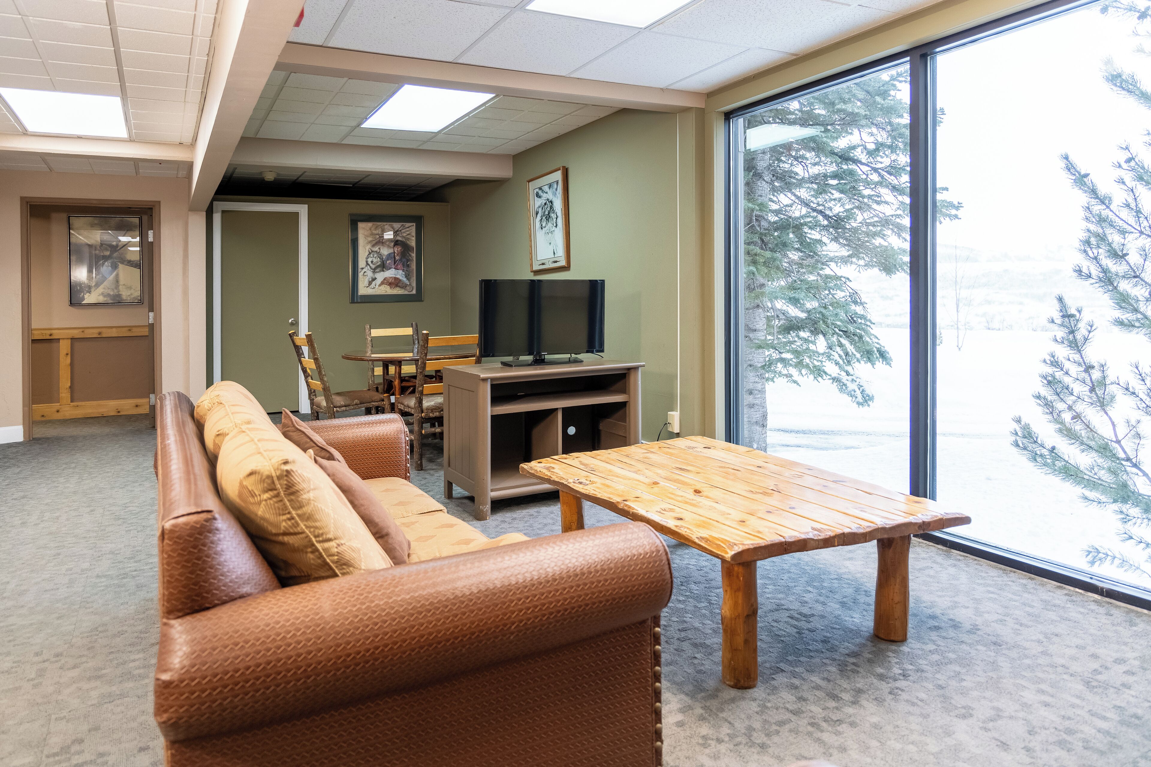 A furnished living room with a sofa, a wooden table, and a television on a stand.