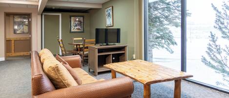 Un salon meublé comprenant un canapé, une table en bois et un téléviseur posé sur un meuble.