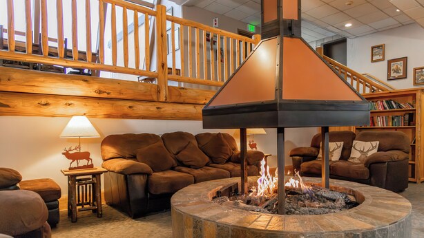 A cozy living room with a stone fire pit, leather sofas, and a wooden staircase. - Legacy Vacation Resorts - Steamboat Hilltop (Steamboat Springs)
