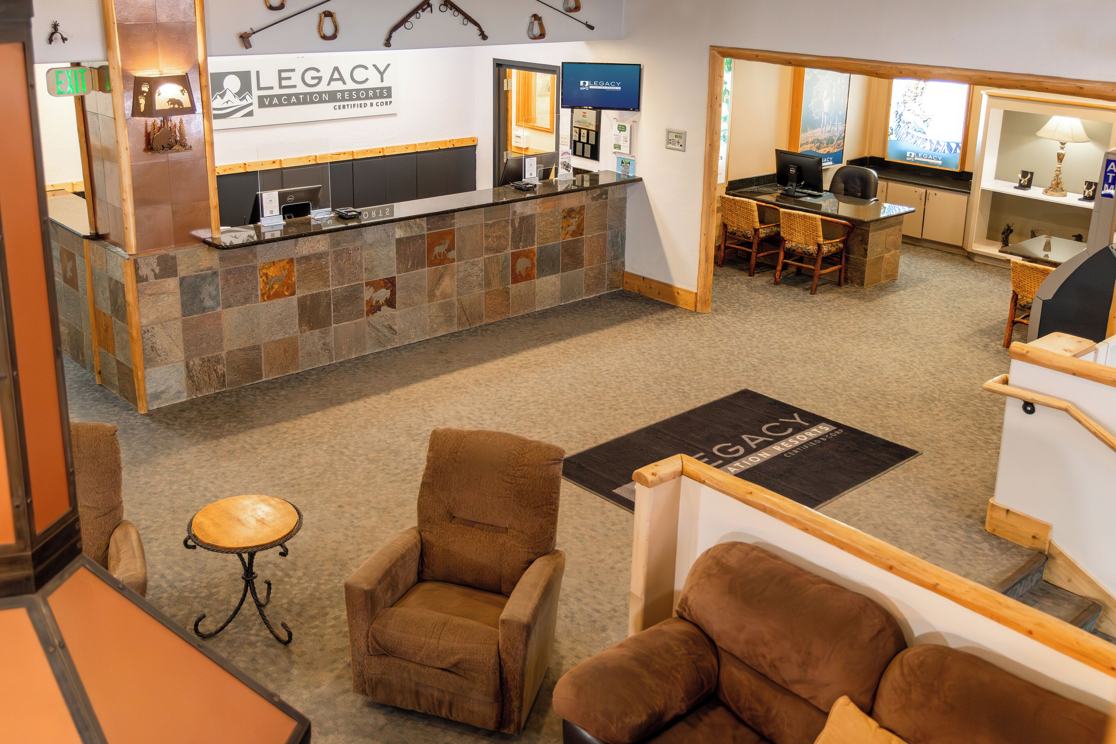 A reception area with a stone counter, a desk, and two brown armchairs.