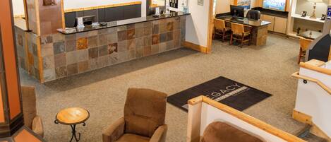 A reception area with a stone counter, a desk, and two brown armchairs.