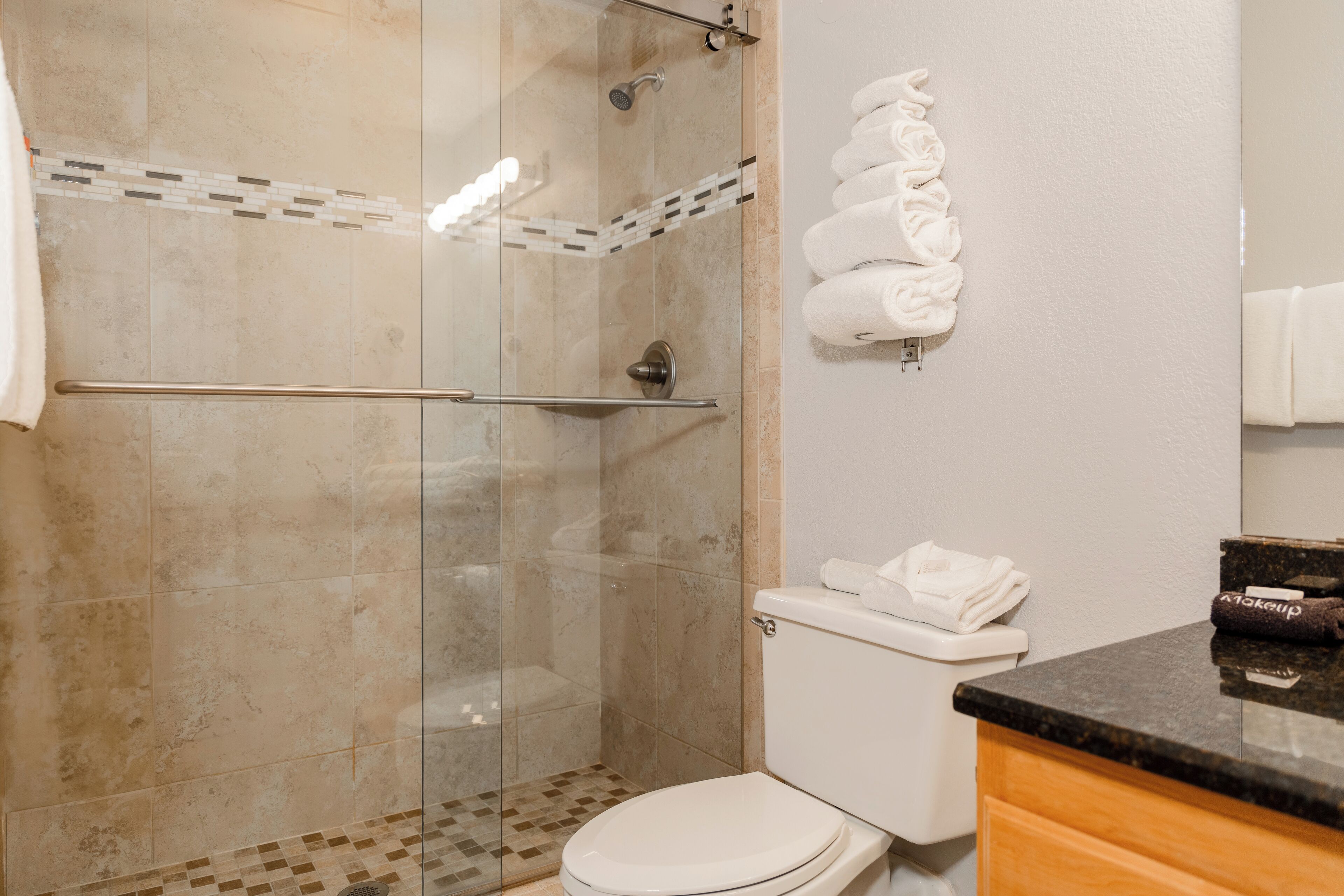 A bathroom with a glass-enclosed shower, a toilet, and a sink with a countertop.