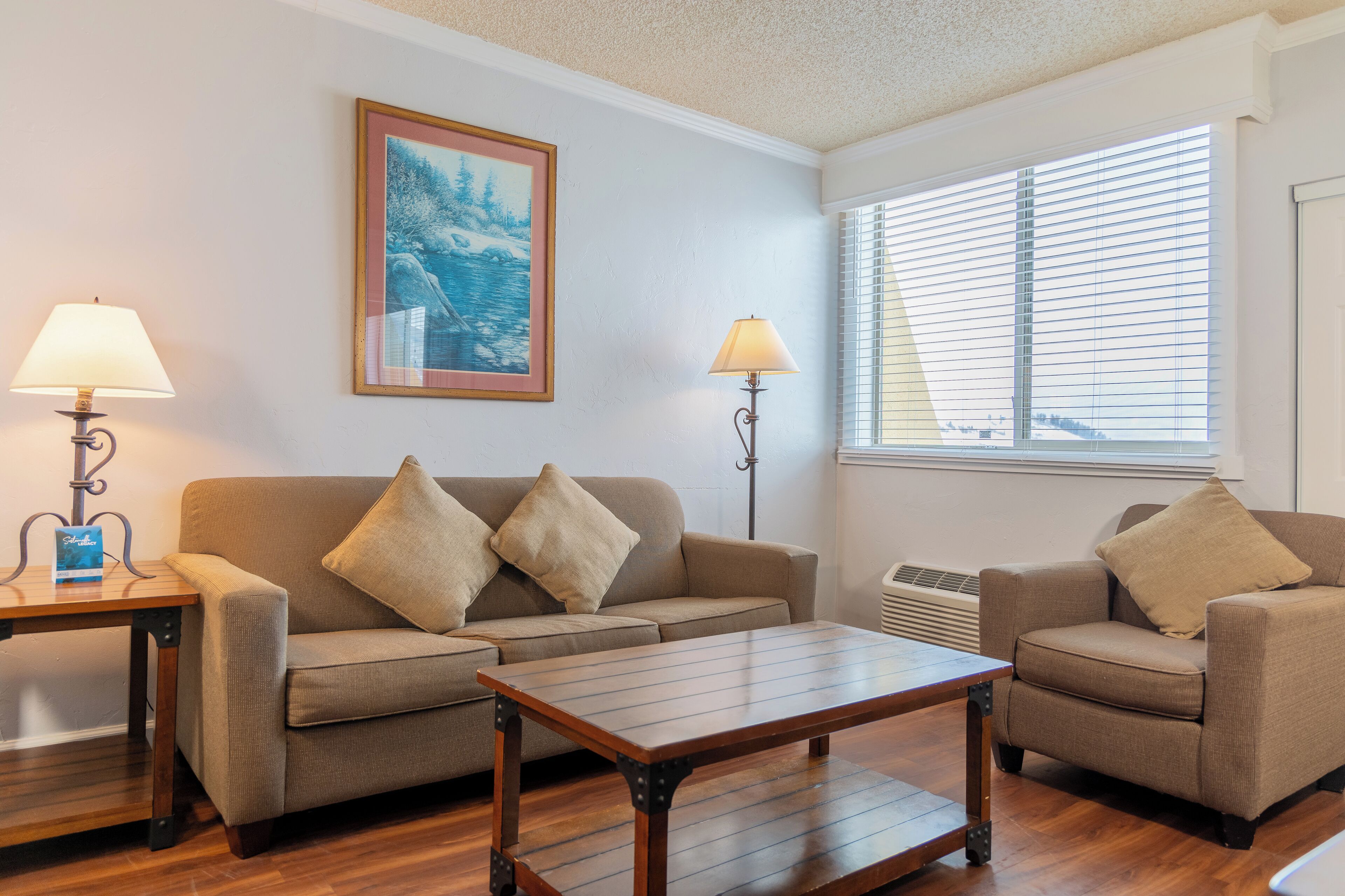 A living room with a sofa, two armchairs, a coffee table, and two floor lamps.