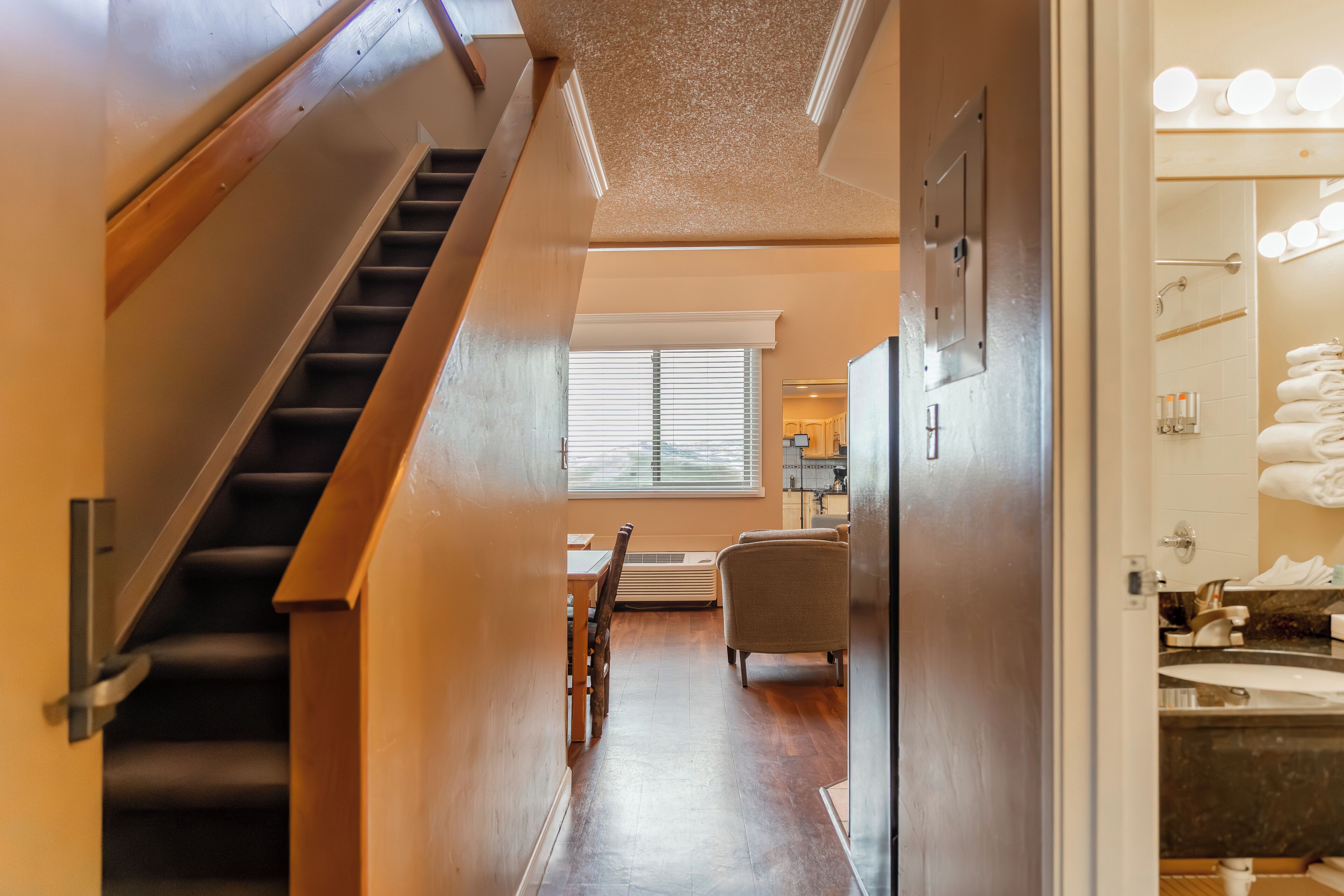 A hallway with a staircase, a dining area, and a bathroom with a sink and towel rack.