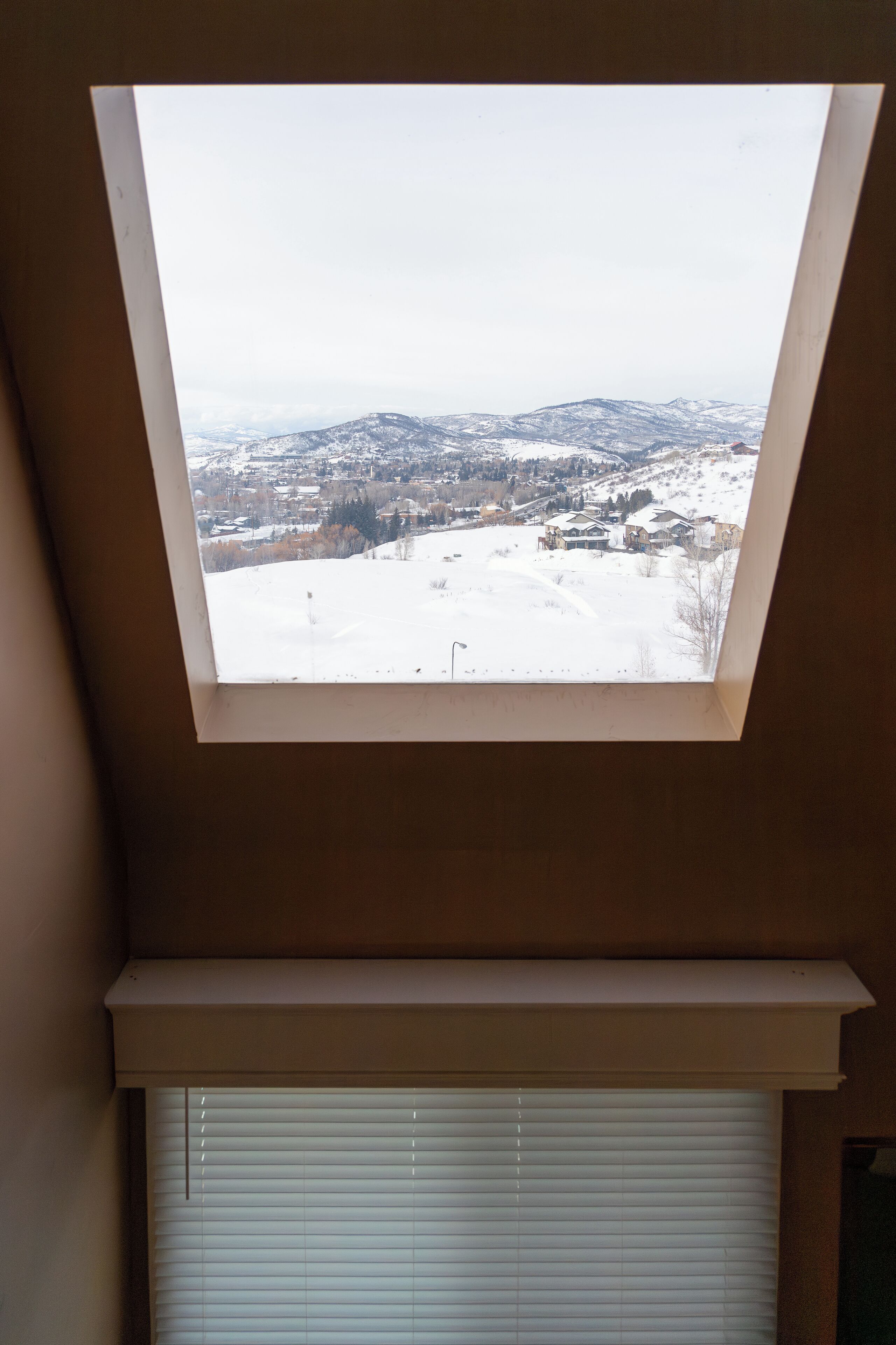 A skylight with a view of a snowy landscape and buildings.
