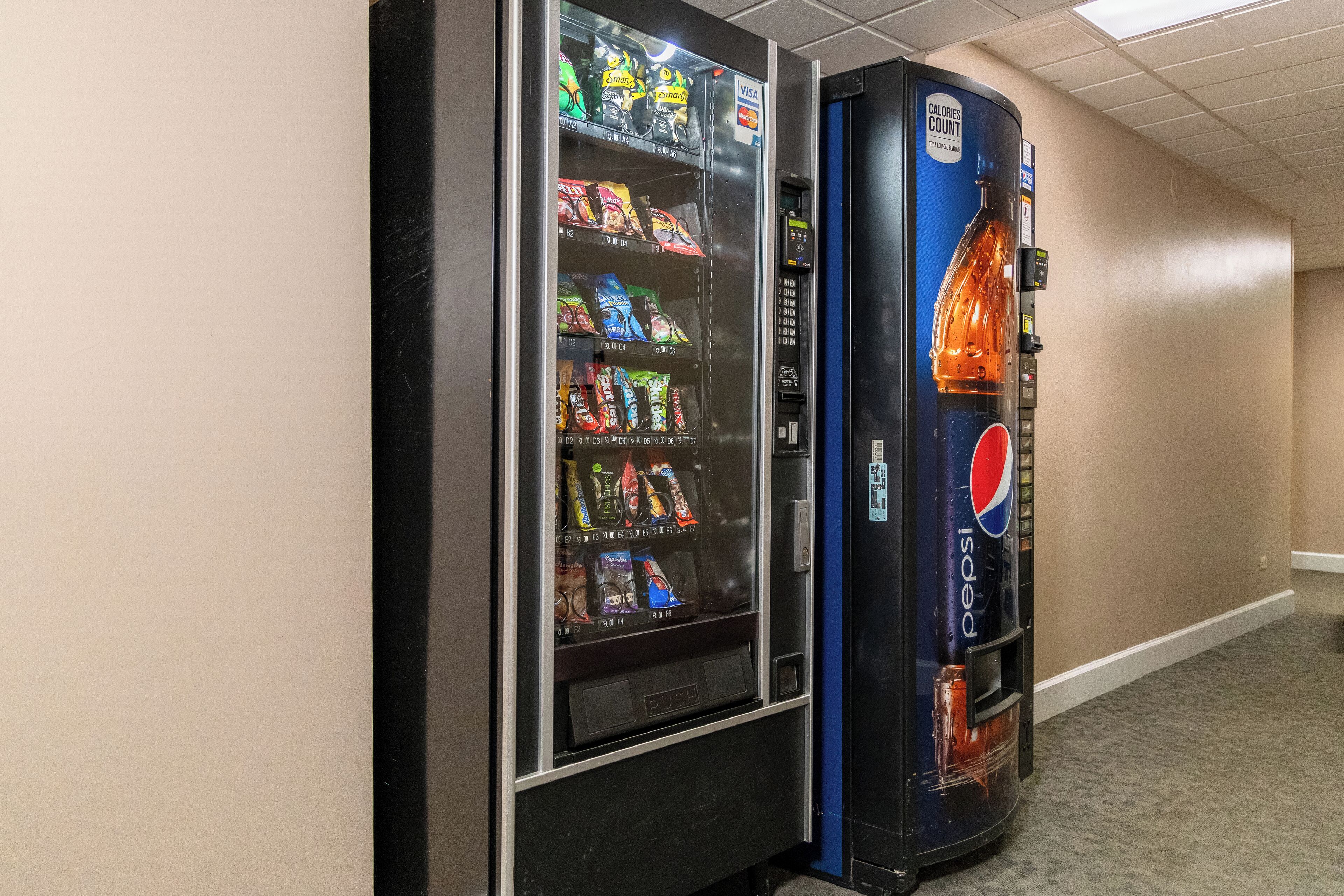 A vending machine with snacks and a Pepsi dispenser in a hallway.