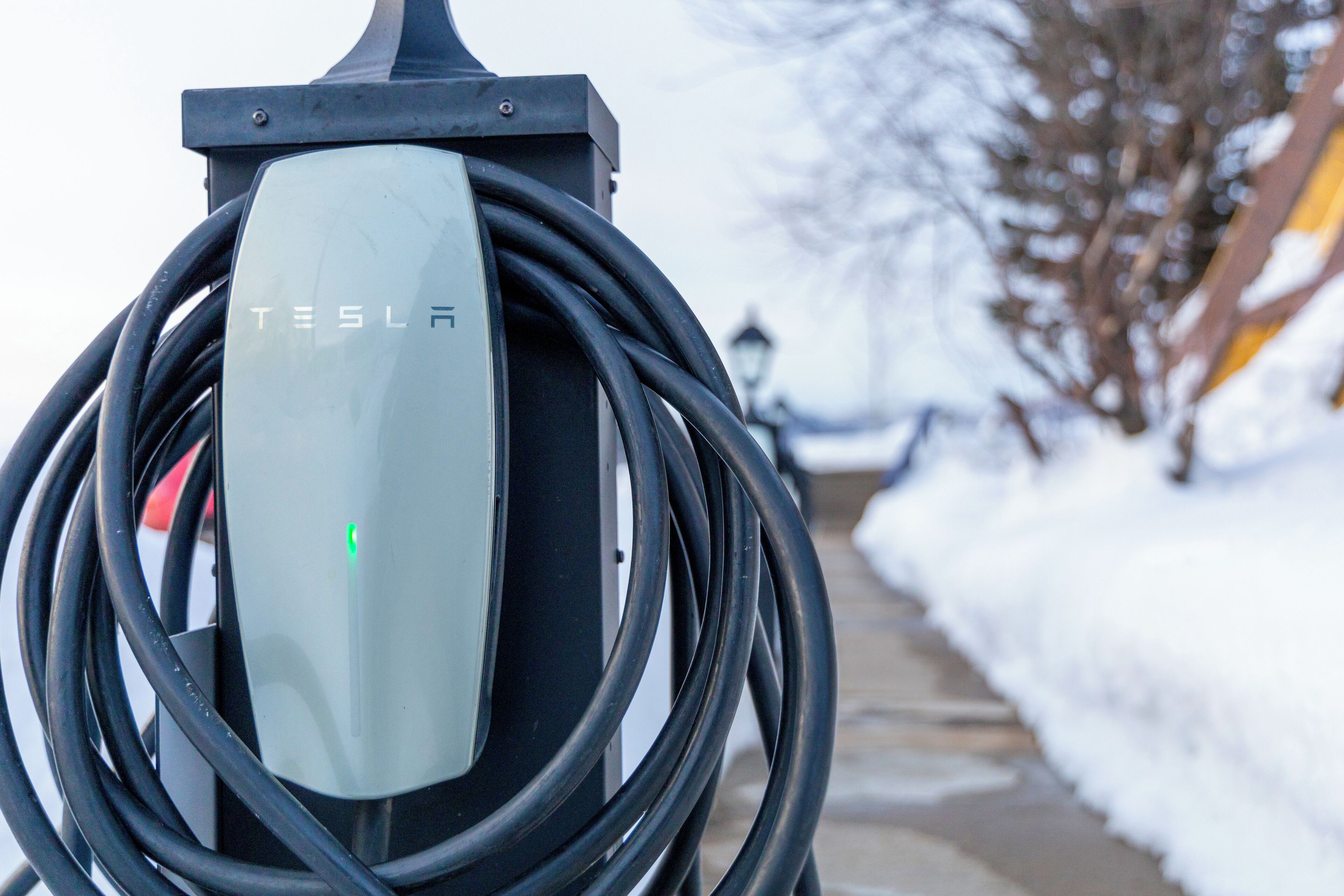 A Tesla electric vehicle charging station with a visible charging cable.