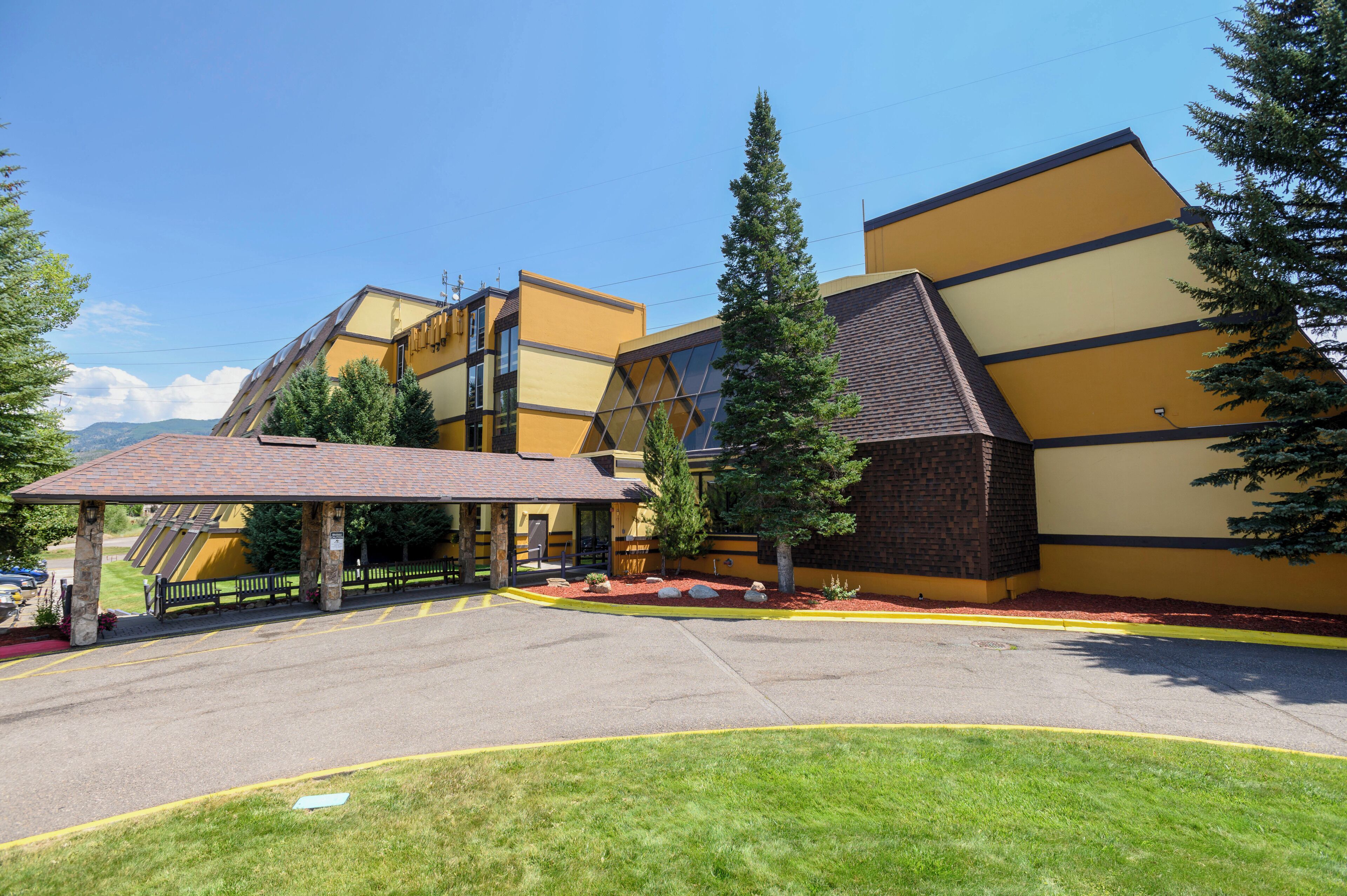 A modern building with a sloped roof, a covered entrance, and a parking area with marked spaces.