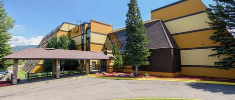 A modern building with a sloped roof, a covered entrance, and a parking area with marked spaces.