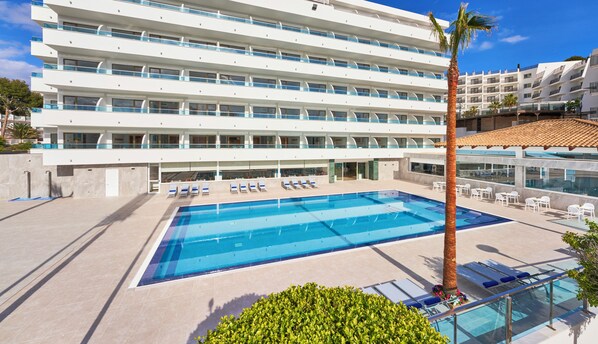 A hotel with a large pool, multiple balconies, and a modern architectural design.