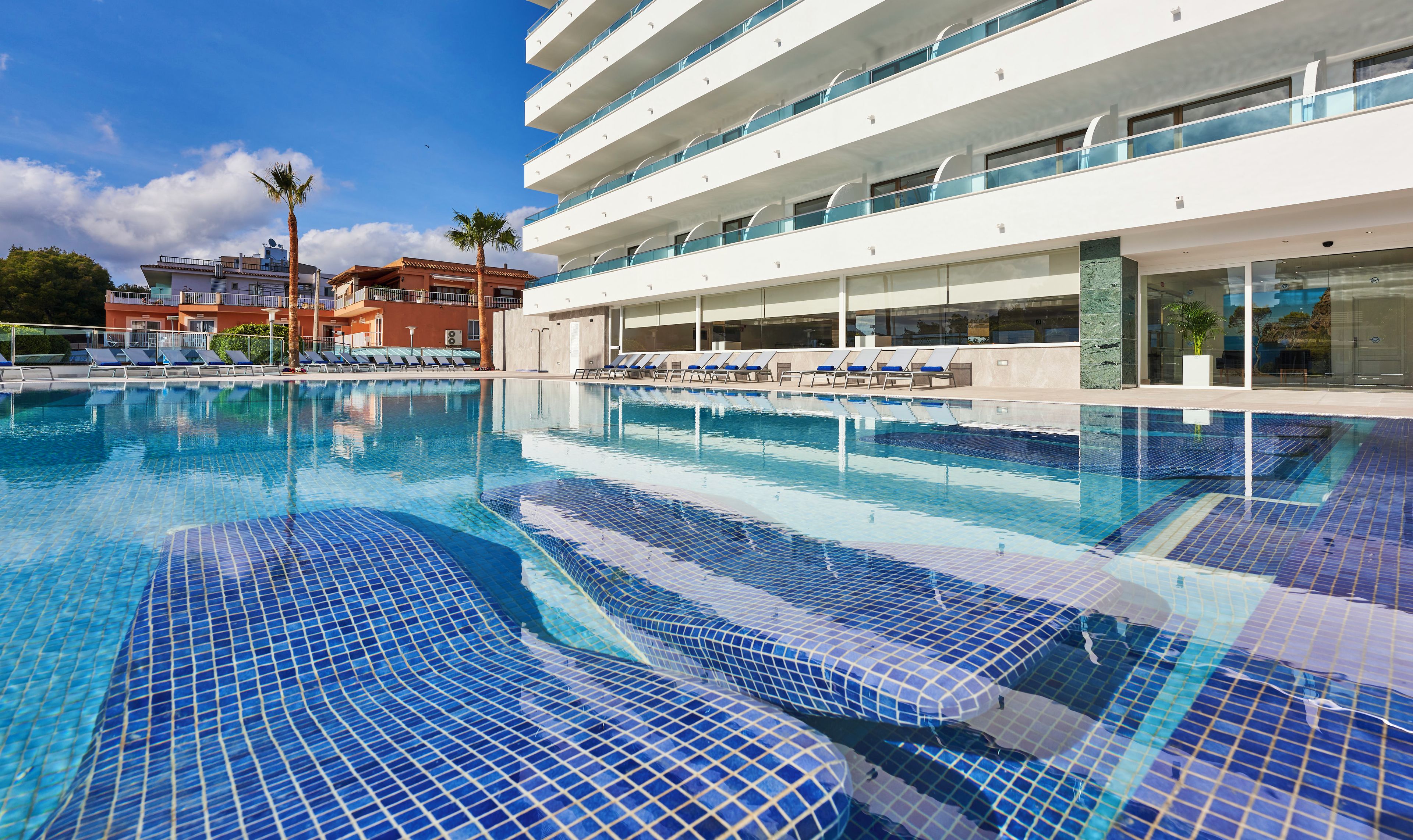 Una piscina al aire libre, sombrillas, tumbonas