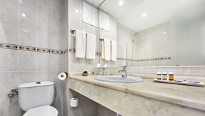 Un baño con inodoro, lavamanos y espejo.