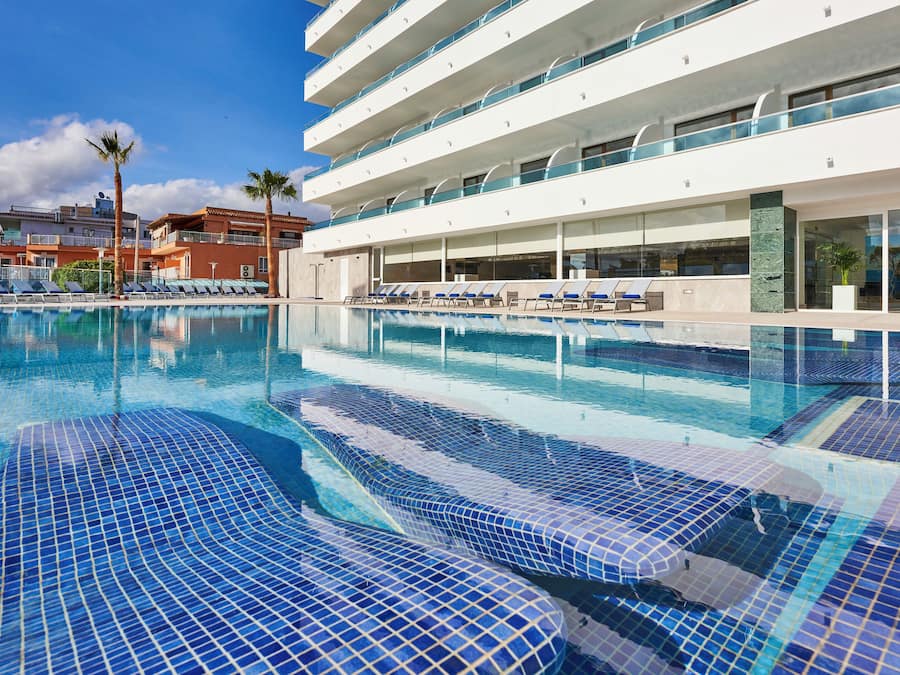 Una piscina al aire libre, sombrillas, tumbonas