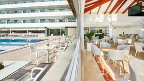 Un moderno vestíbulo de hotel con zona de piscina, asientos al aire libre y un bar.