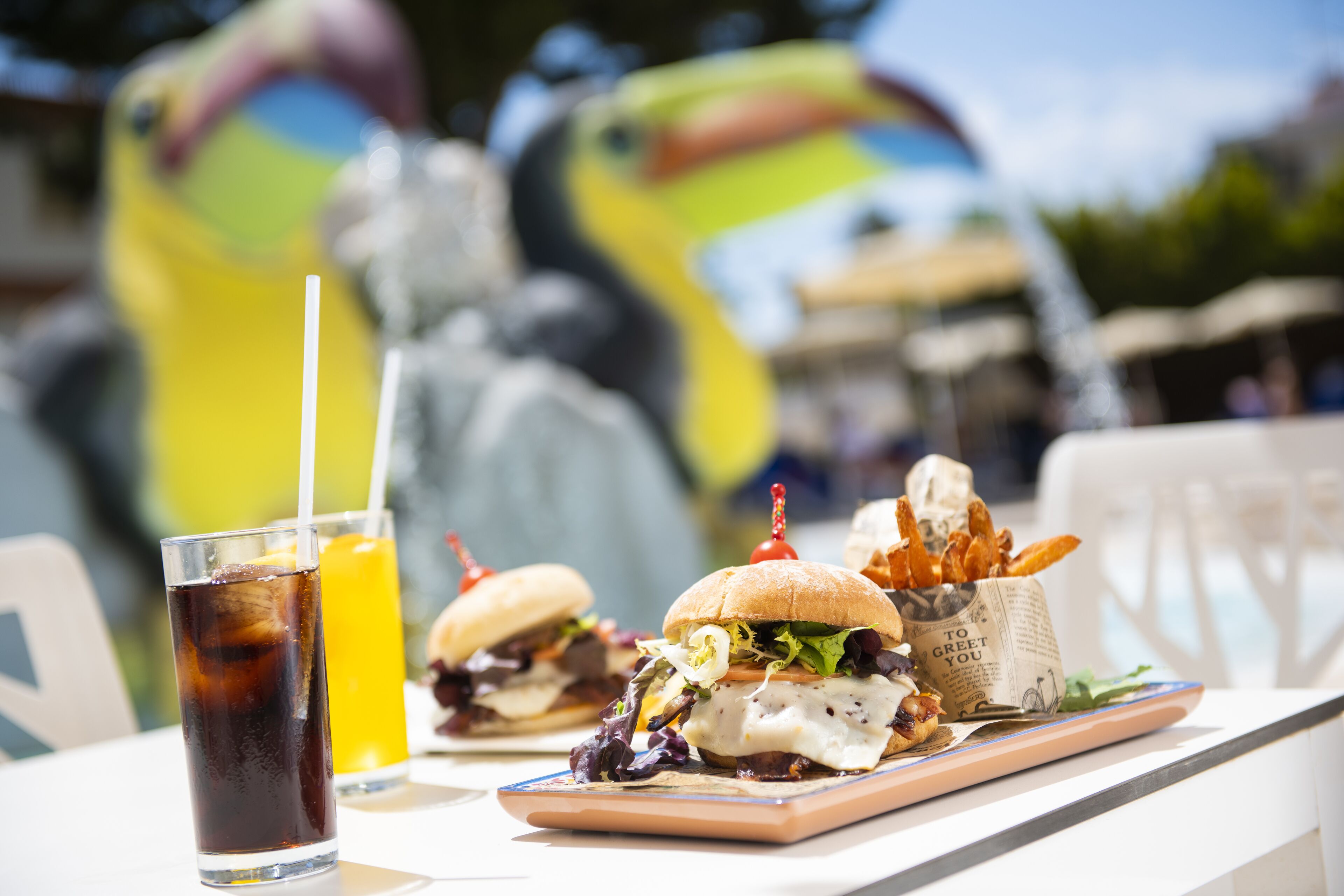 Ein Esstisch mit einem Burger, Pommes und einem Getränk.