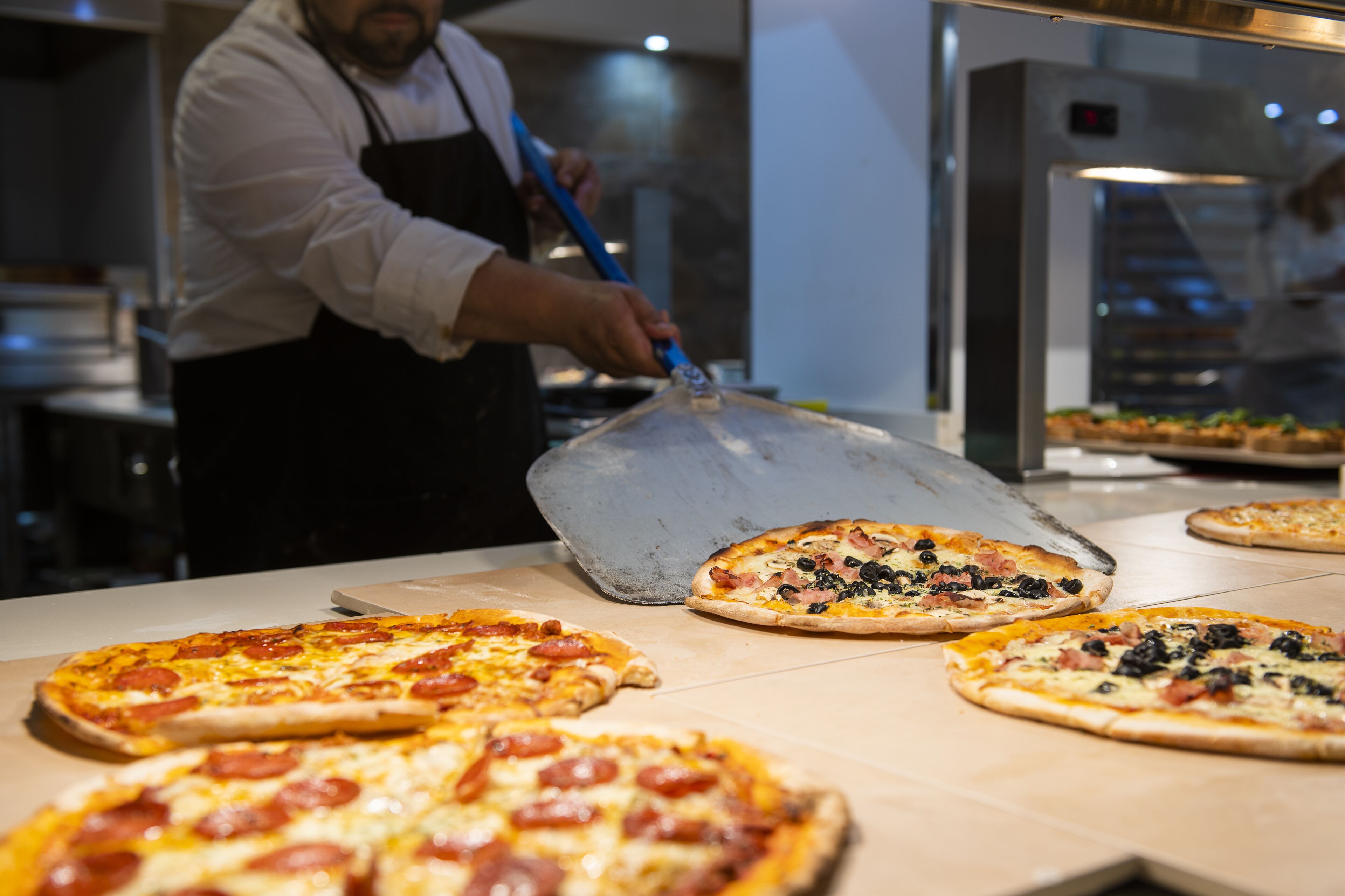 Un pizzaiolo préparant des pizzas dans une cuisine.