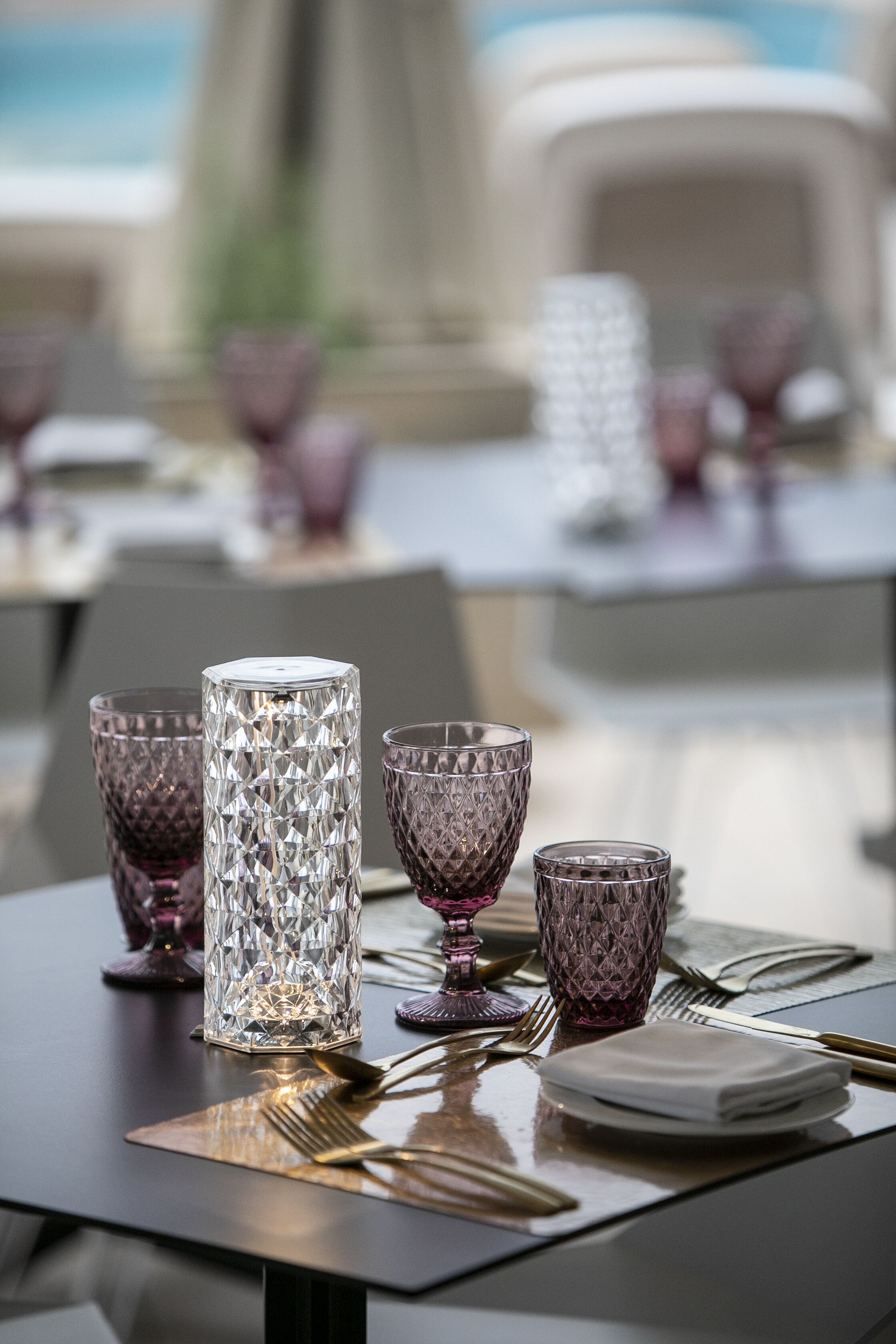 Mesa de comedor dispuesta con copas de cristal y cubiertos, con vista al mar.