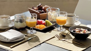 A breakfast table with various food items and drinks, overlooking a beach with umbrellas and the sea. - Hotel Condesa Mallorca (Alcúdia)