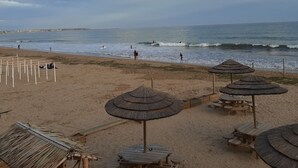Een strand met parasols, houten tafels en een helder uitzicht op de oceaan.