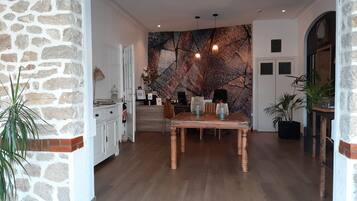 Un comedor con mesa y sillas de madera, una pared de piedra y una obra de arte moderna en la pared de fondo.