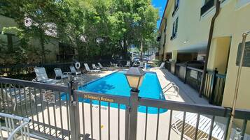 A swimming pool with a 34 swimmers maximum sign, surrounded by lounge chairs and a fence.