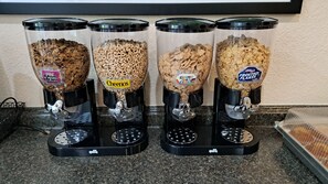 Four cereal dispensers with different brands on a countertop.