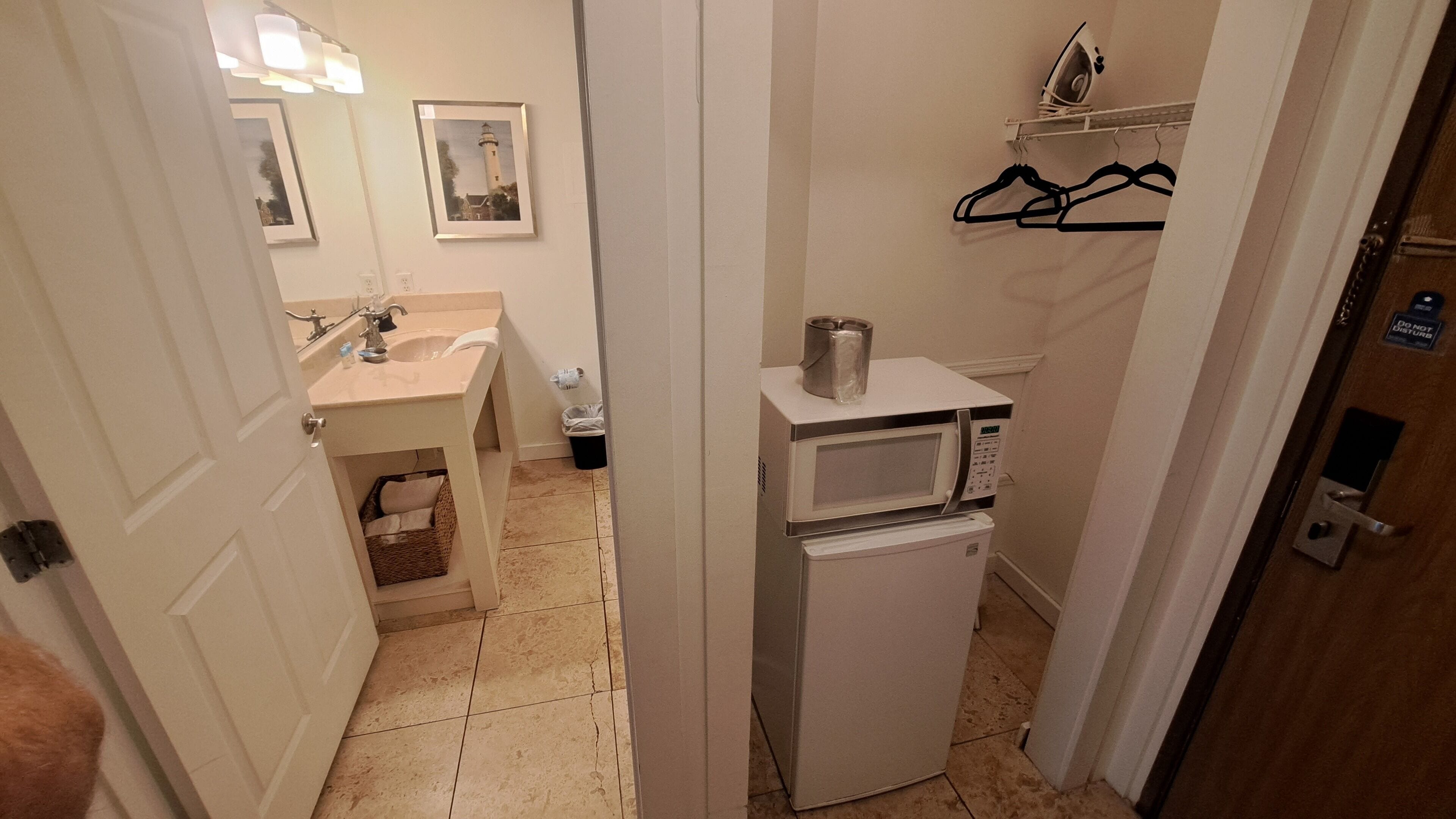 A compact bathroom with a sink, mirror, and a microwave.