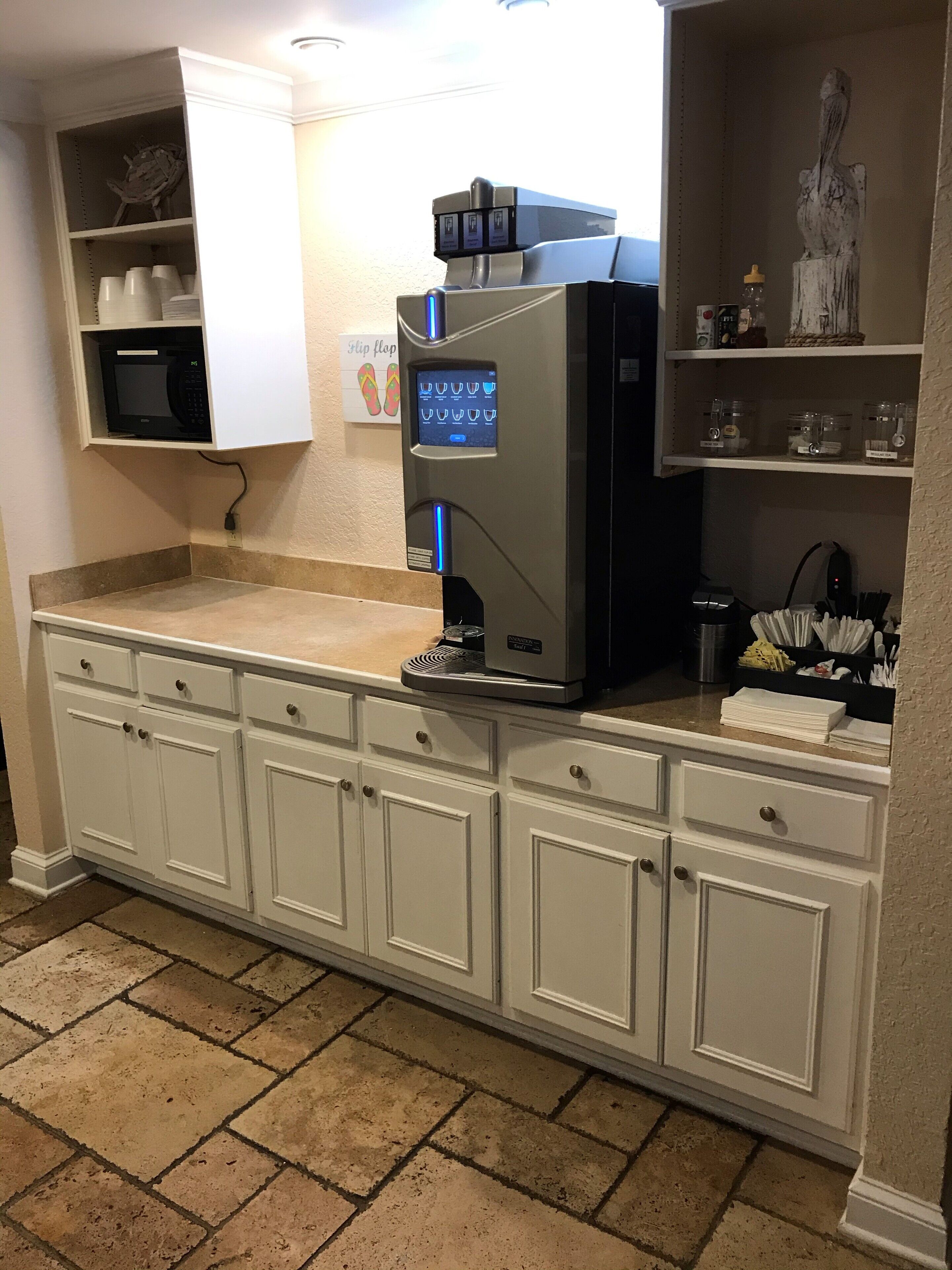 A kitchen with a built-in coffee machine, a microwave, and a refrigerator.