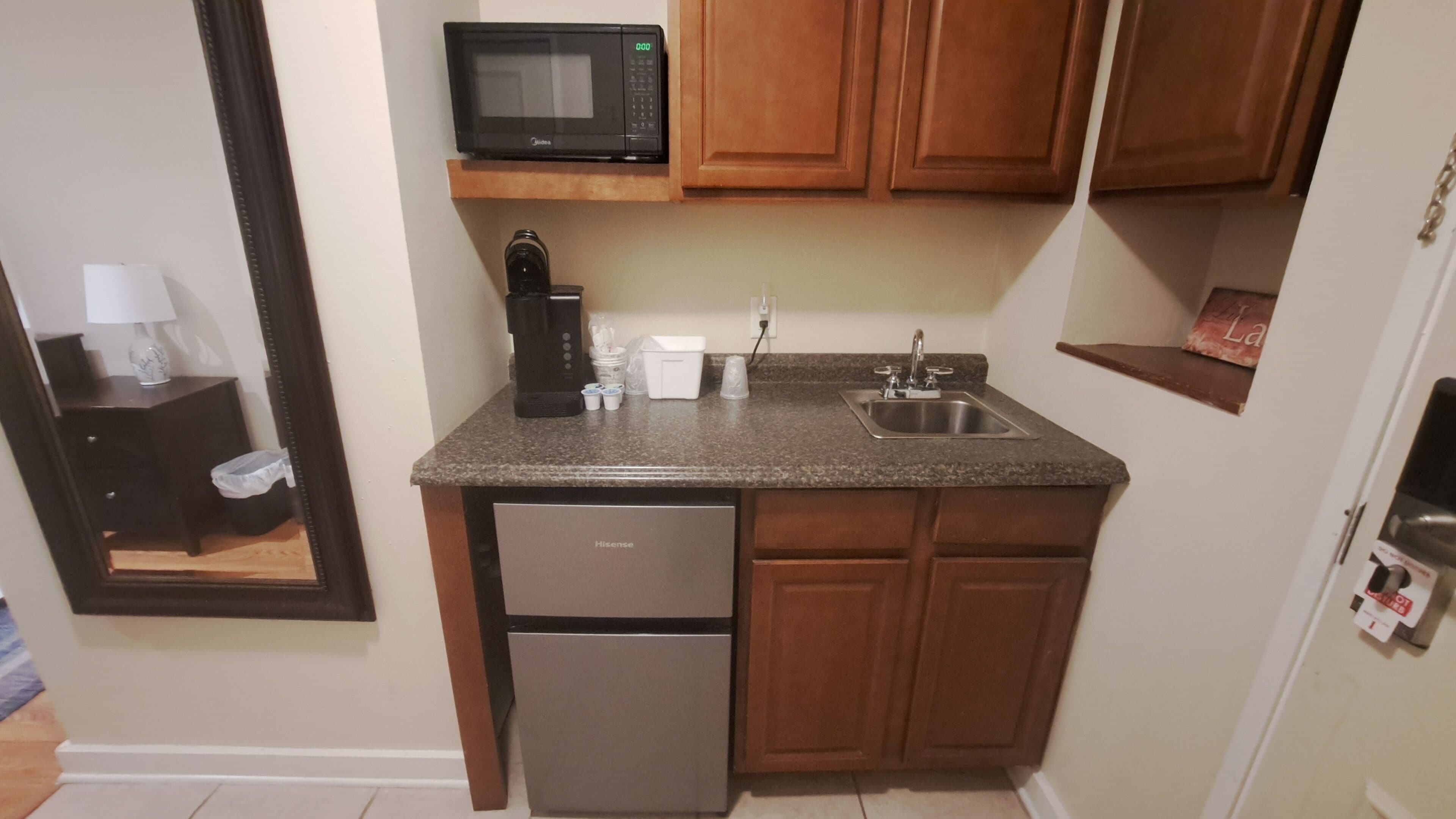 Una cocina compacta con microondas, cafetera y lavabo.