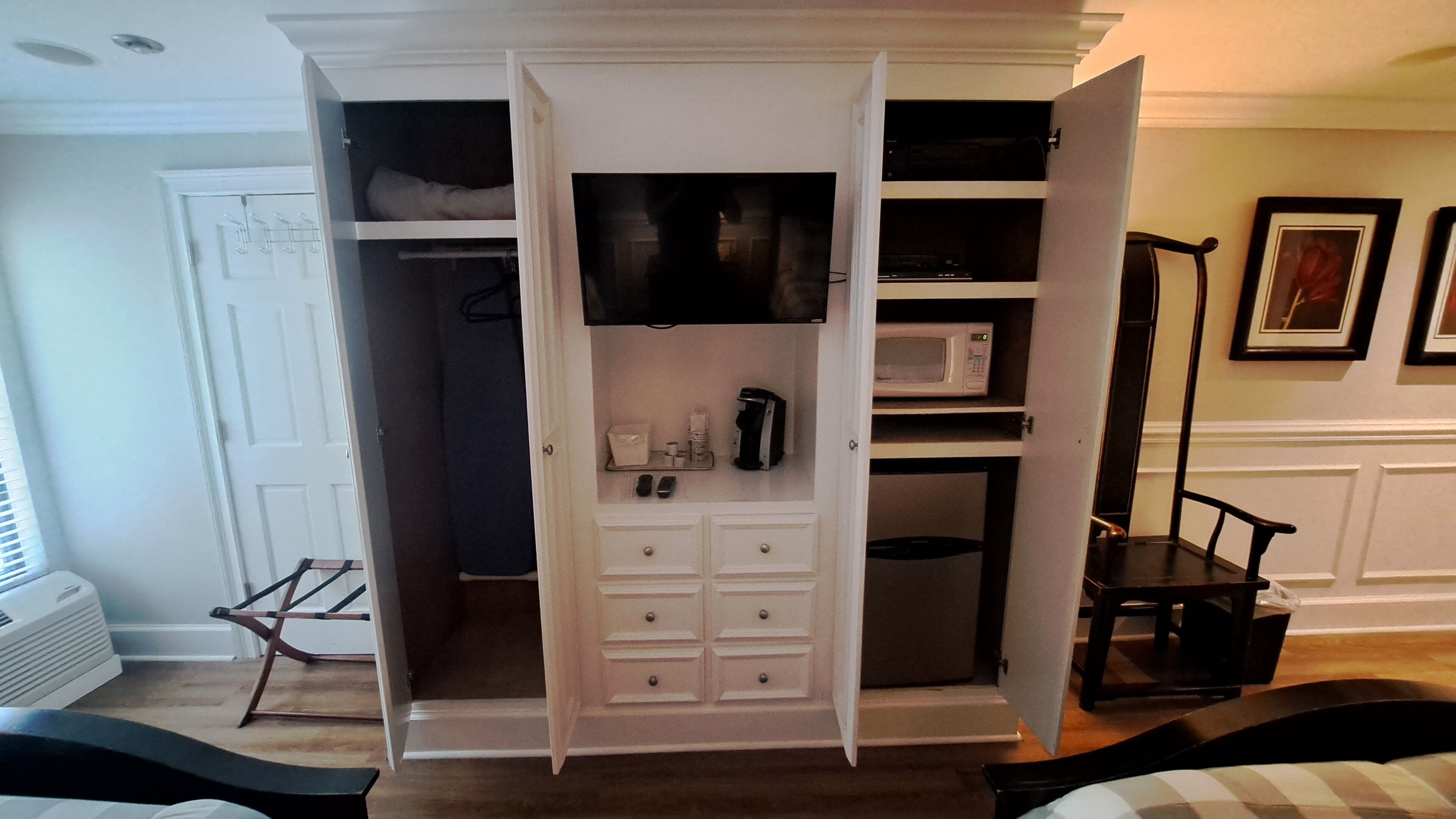 A walk-in closet with a microwave, coffee maker, and storage drawers.