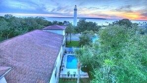 A house with a swimming pool, a tall lighthouse in the background, and a view of the sea. - Saint Simons Inn by the Lighthouse (St. Simons Island)