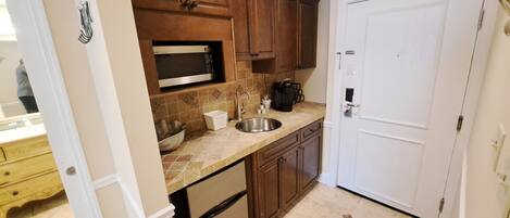 A kitchen with wooden cabinets, a stainless steel sink, a microwave, a coffee maker, and a dishwasher.