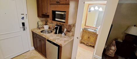 A compact kitchen with a dishwasher, a microwave, a sink, and wooden cabinets.