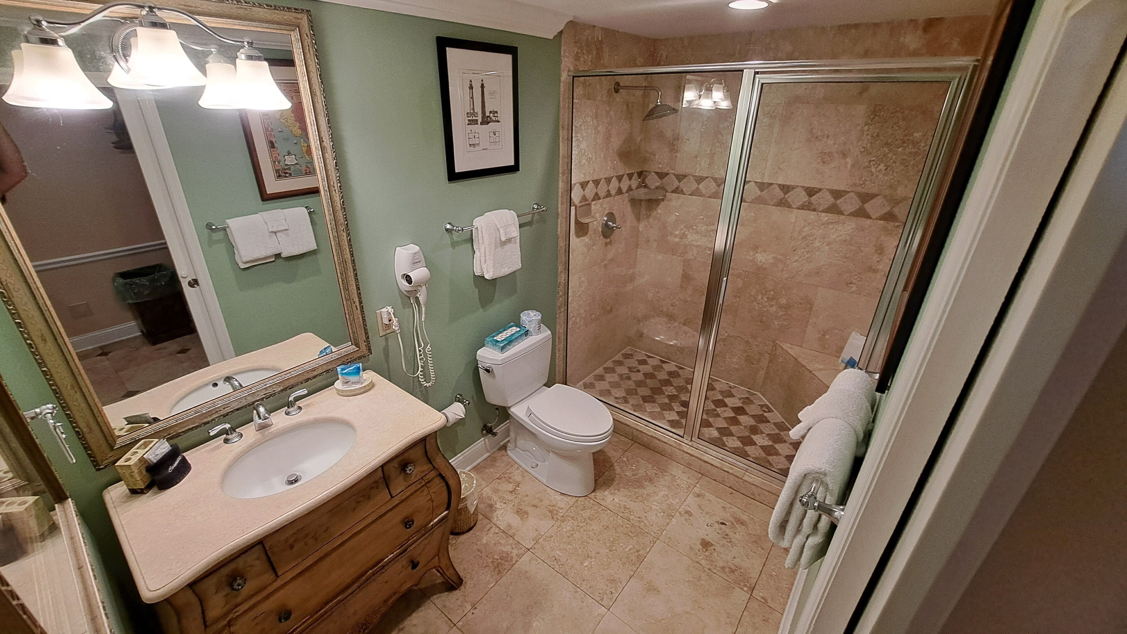 A bathroom with a sink, vanity, toilet, and a glass-enclosed shower area.
