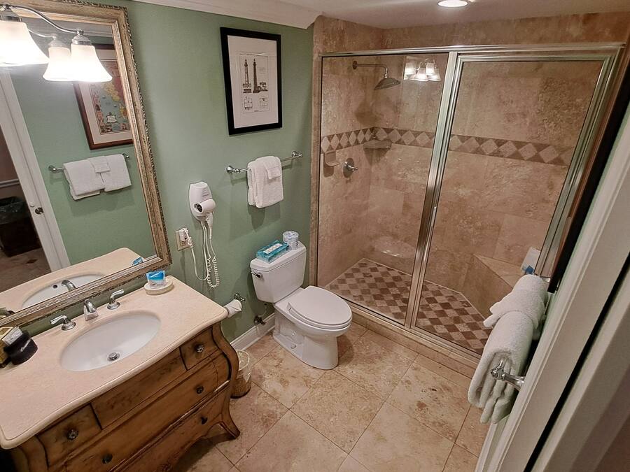 A bathroom with a sink, vanity, toilet, and a glass-enclosed shower area.